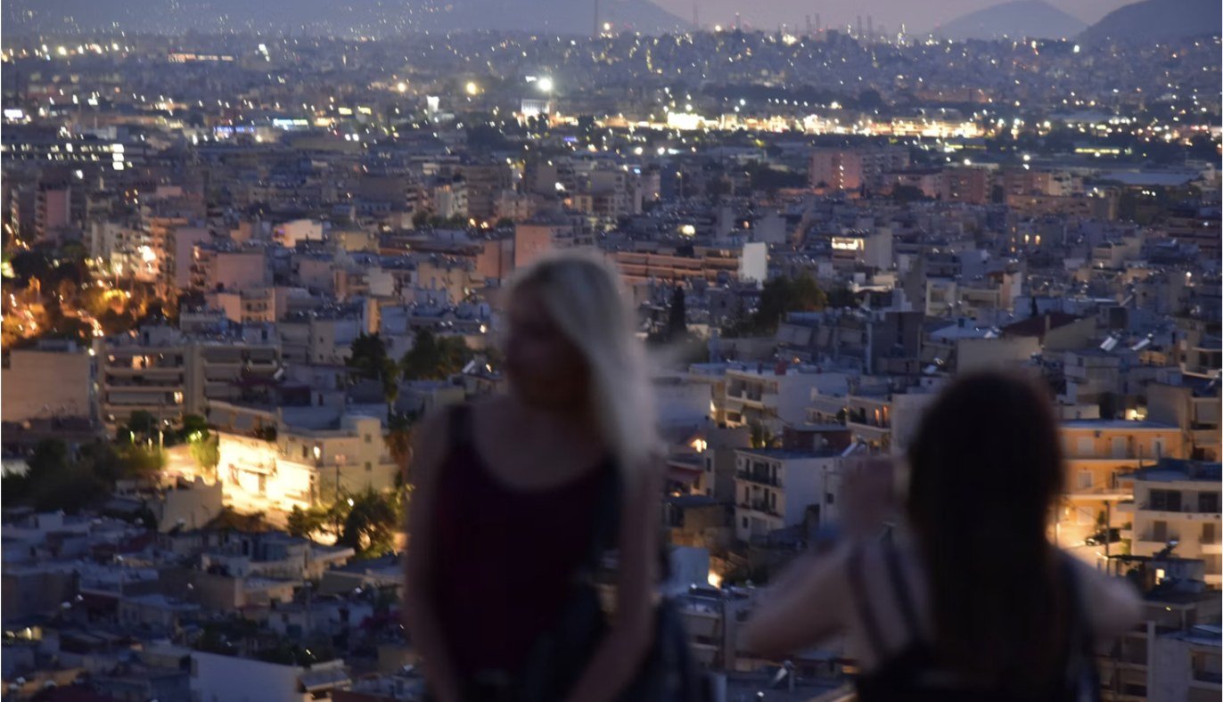 Dos amigas contemplando las luces de la ciudad desde una terraza al anochecer