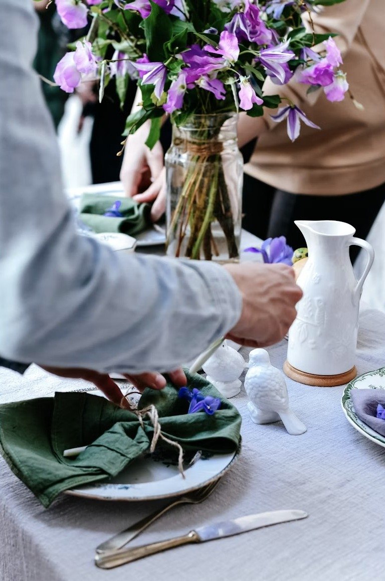 Dos personas preparando un arreglo floral y vistiendo la mesa antes de una sesión