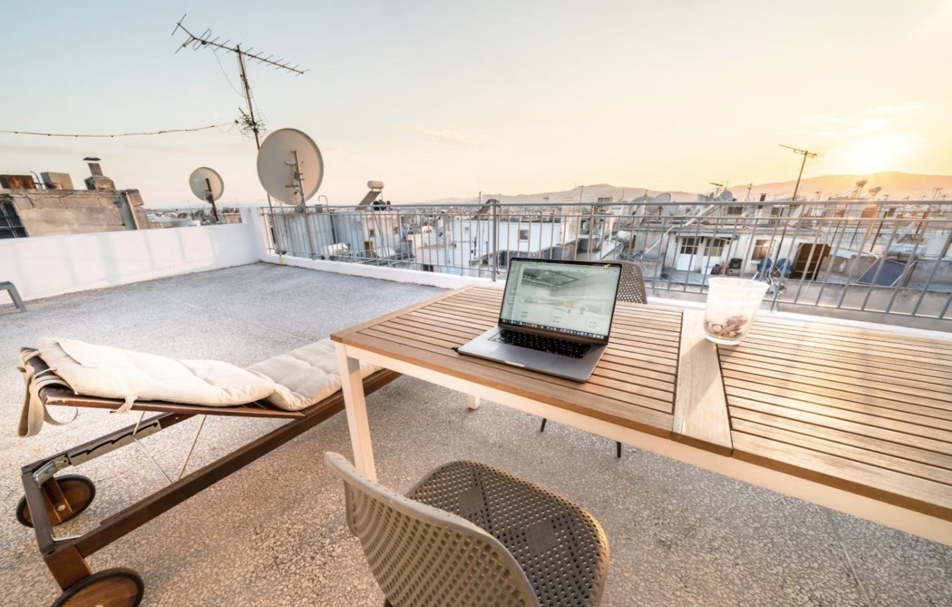 Portátil abierto sobre una mesa en una azotea al atardecer, revisando el material del día