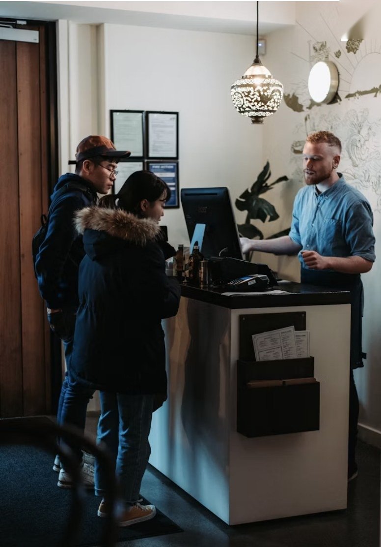 Huéspedes haciendo el check-in con el recepcionista en el mostrador de un hotel a su llegada