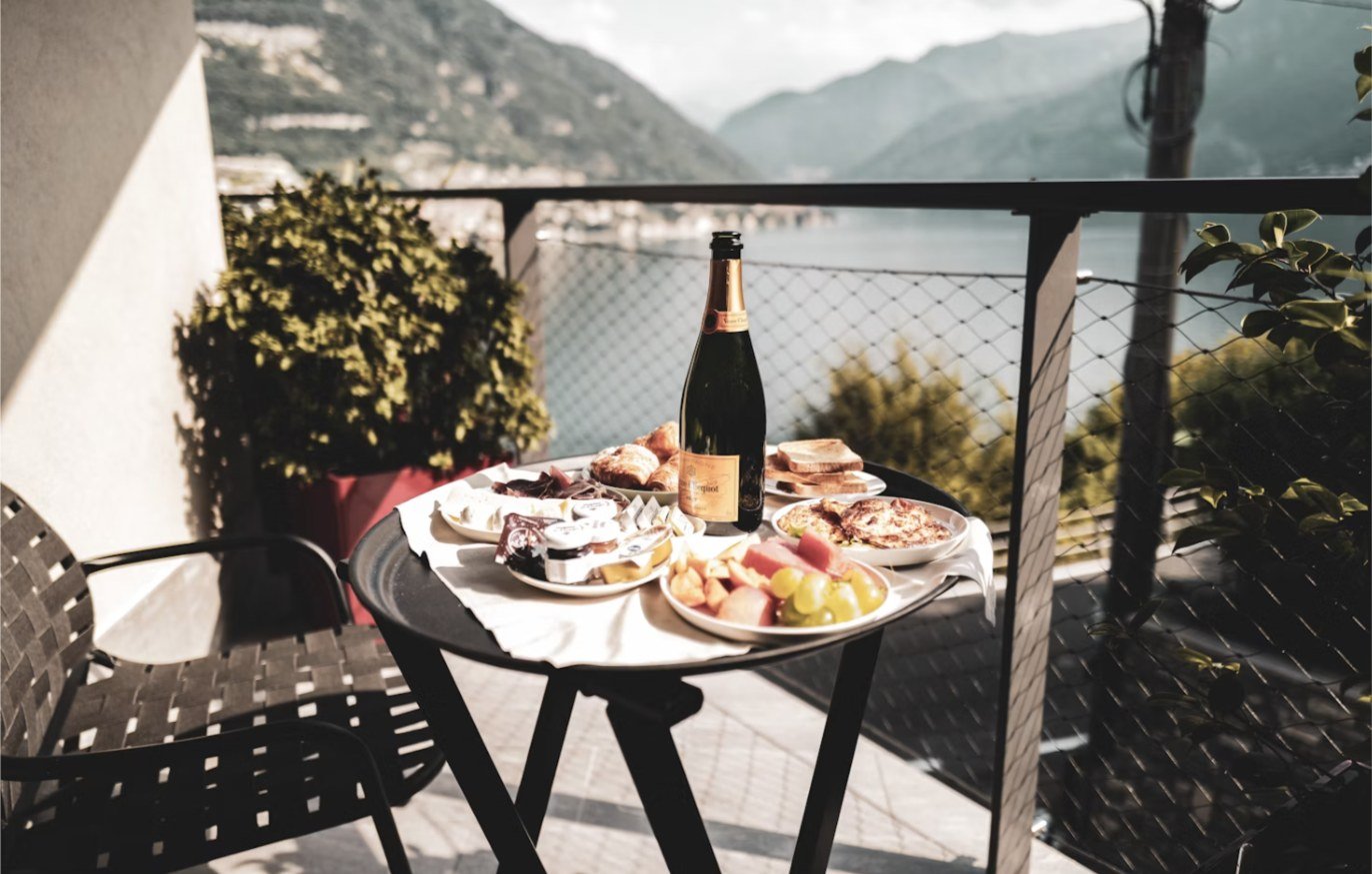 Desayuno servido en un balcón con vistas a las montañas y un lago