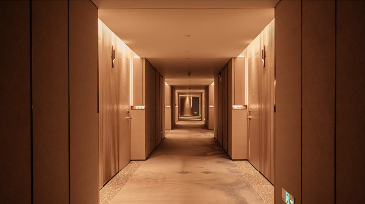 Pasillo de habitaciones con luz cálida y puertas alineadas en perspectiva